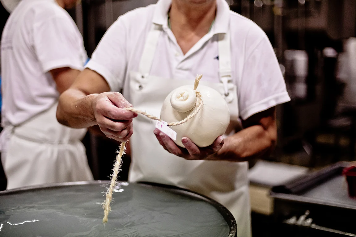 Hands working a string-tied stretched-curd cheese